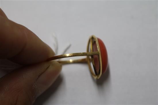 A yellow metal and oval cabochon coral ring, size R.